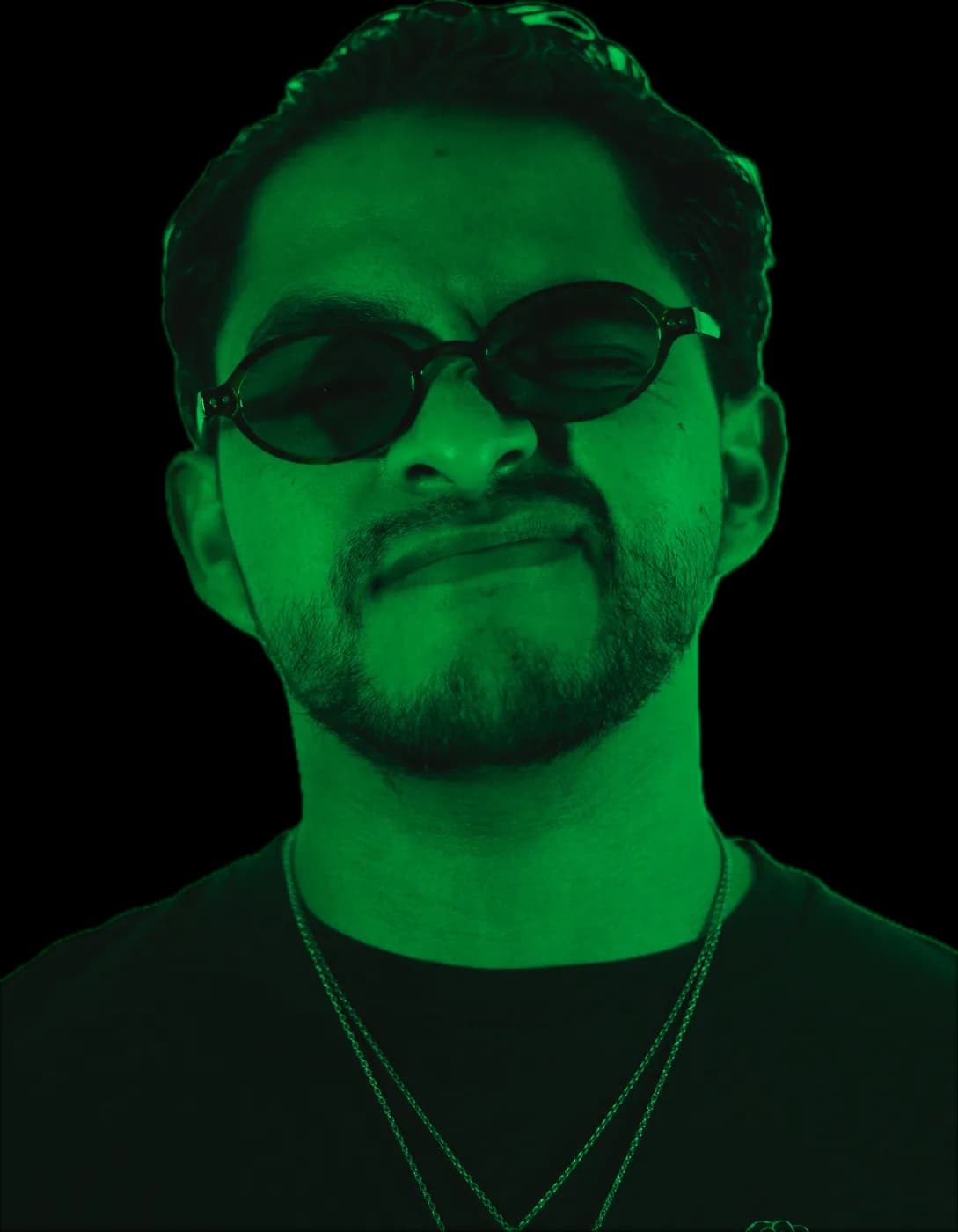 Retrato de Greek con lentes de sol ovalados y gesto serio, en verde neón